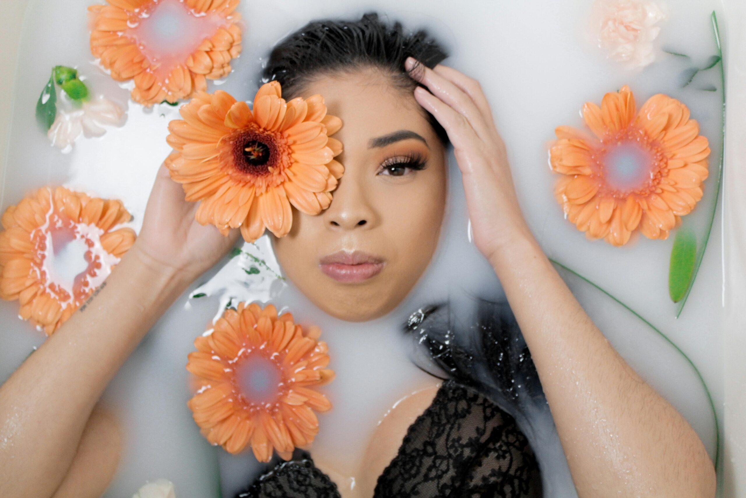 Egy fiatal hölgy fekszik a vizban, naracssárga szinű margarétákat emel az egyik szeméhez, körülötte még elszórva virágok vannak